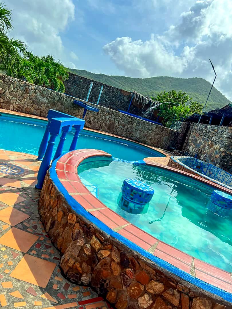 Jacuzzi circular de piedra junto a la piscina, con los cerros de Margarita al fondo